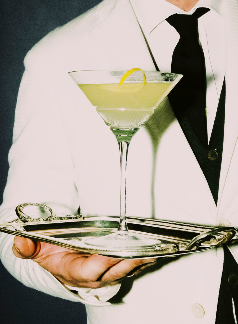 Waiter in white jacket serving a martini on a silver tray